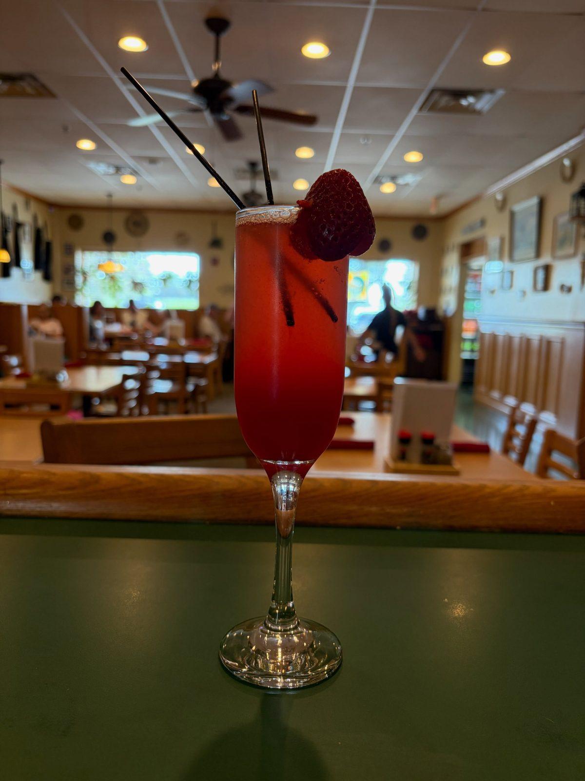 A red drink with a strawberry on the counter overlooking the Pizzeria DiMeo dining room